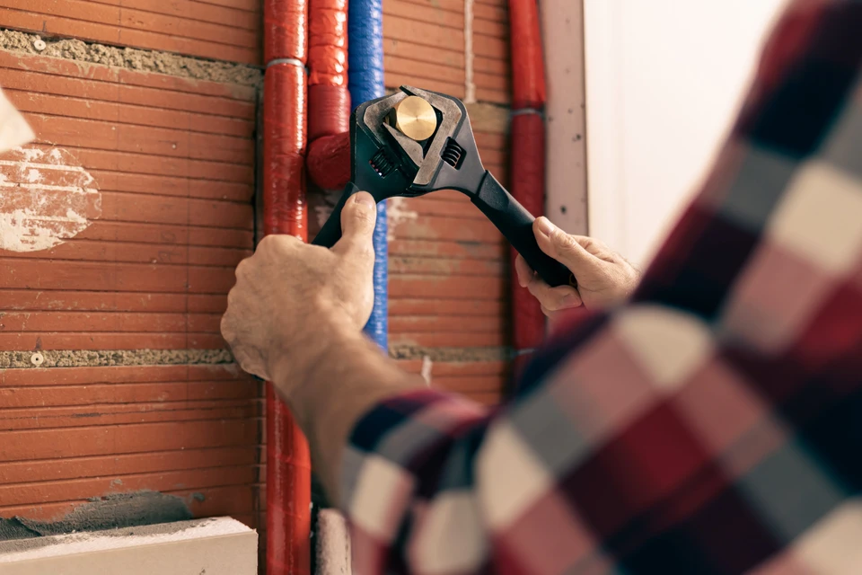 Installation d'eau domestique - le plombier resserre une capsule sur les canalisations d'eau chaude et froide