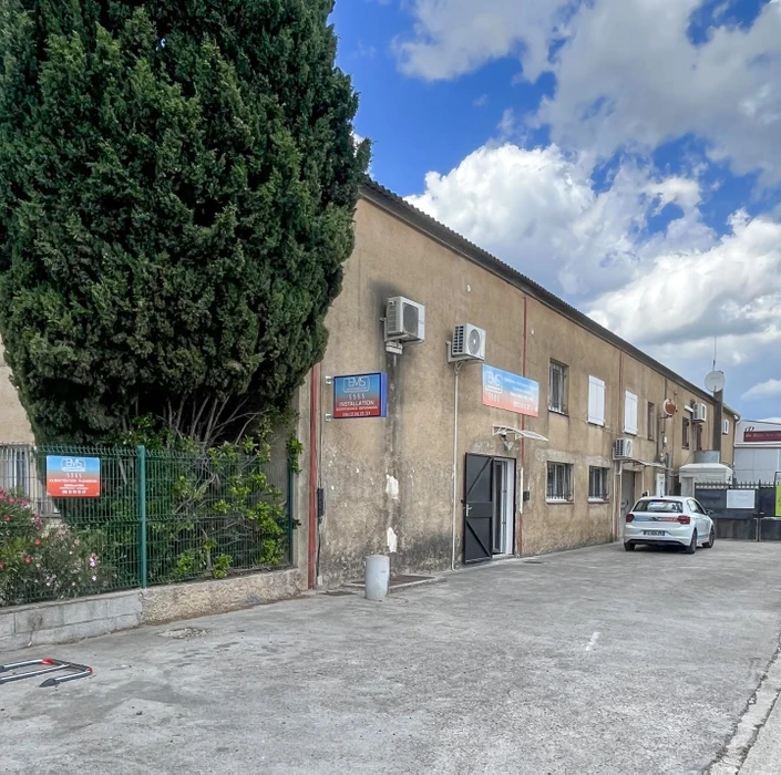 Plombier en salopette bleue travaillant à genoux dans salle de bain moderne, manipulant outils de plomberie