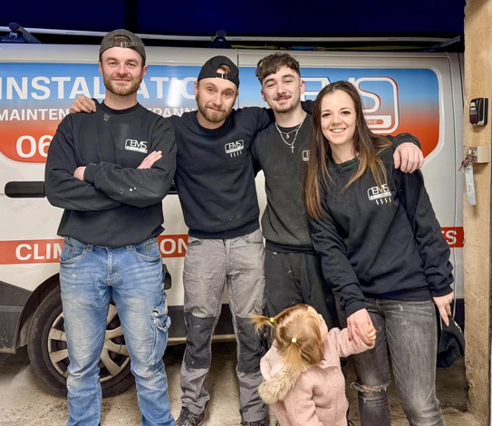 Technicien en plomberie travaillant dans une chaufferie résidentielle, ajustant une canalisation avec une clé à molette rouge