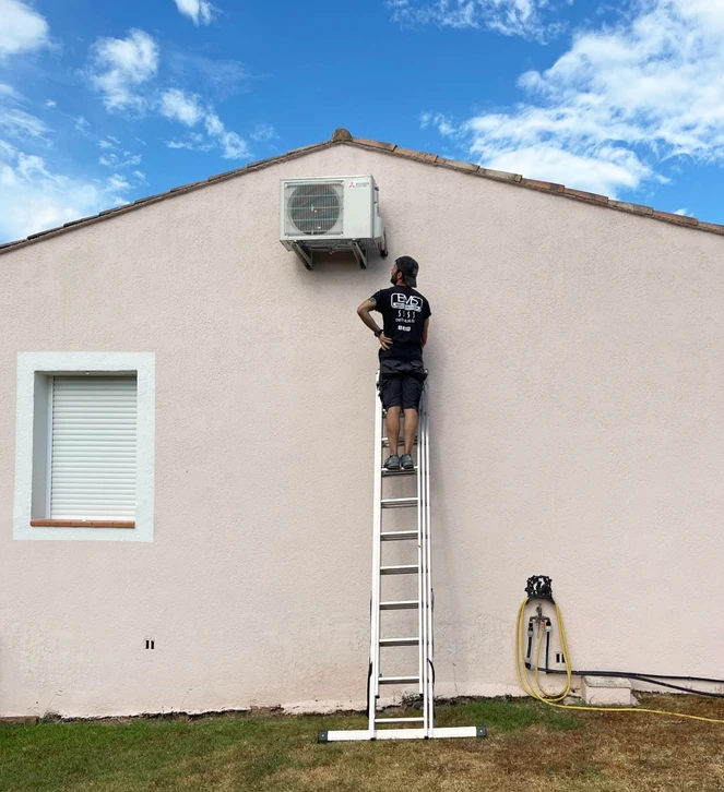 Technicien en climatisation travaillant sur un toit, agenouillé près d'unités de climatisation extérieures, utilisant un ordinateur portable pour diagnostic ou maintenance