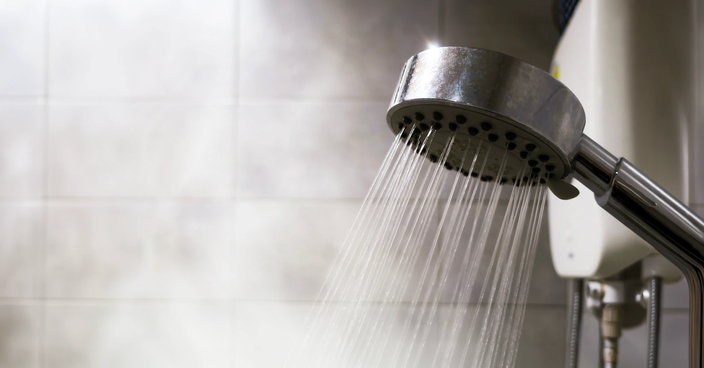 Plombier professionnel en salopette et casquette installant ou réparant un chauffe-eau électrique mural dans une salle de bain moderne