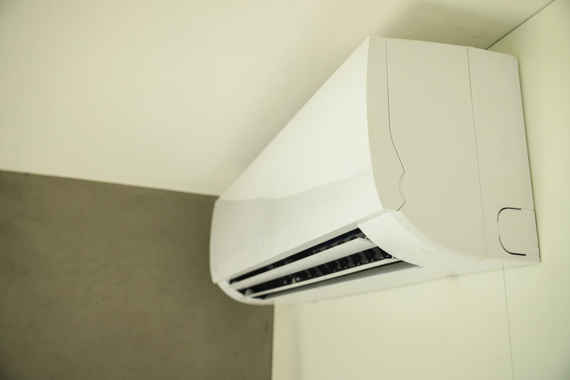 Technicien en combinaison blanche effectue la maintenance d'une unité de climatisation murale split